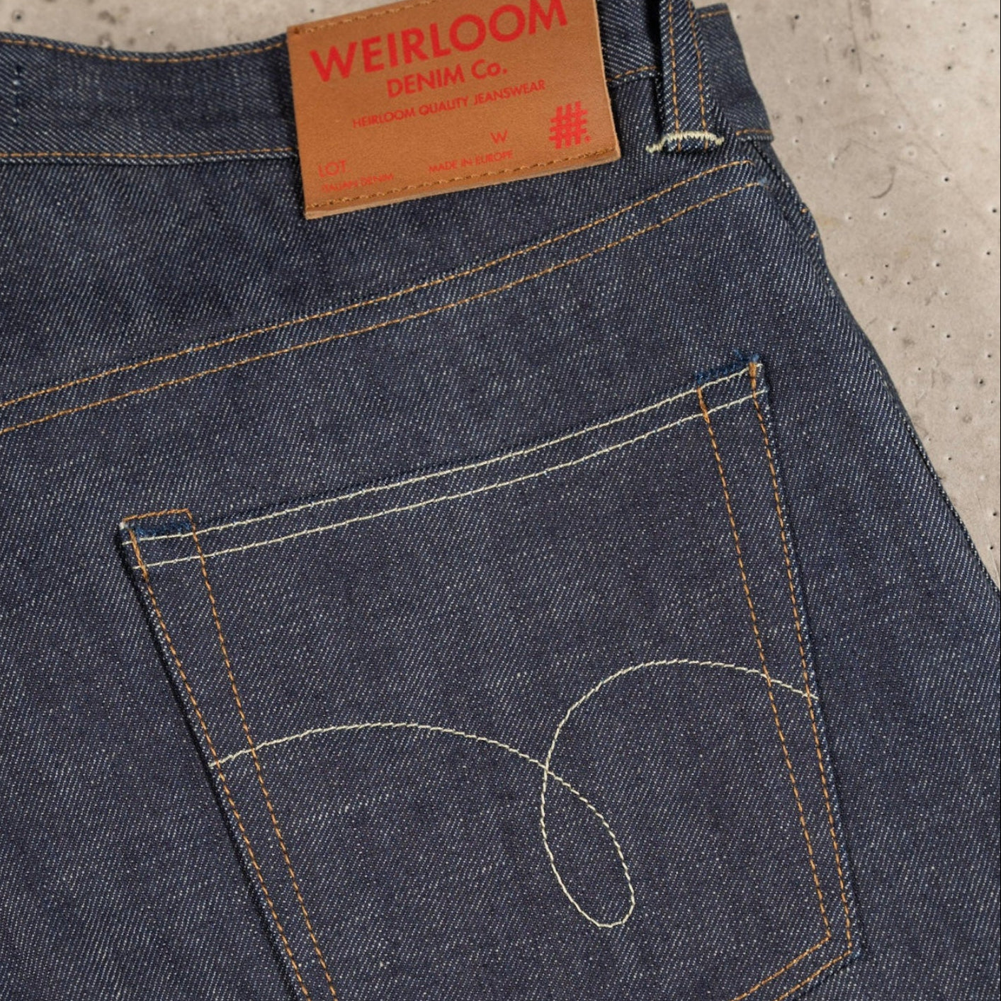 Blue jeans with a visible brand label on a concrete surface